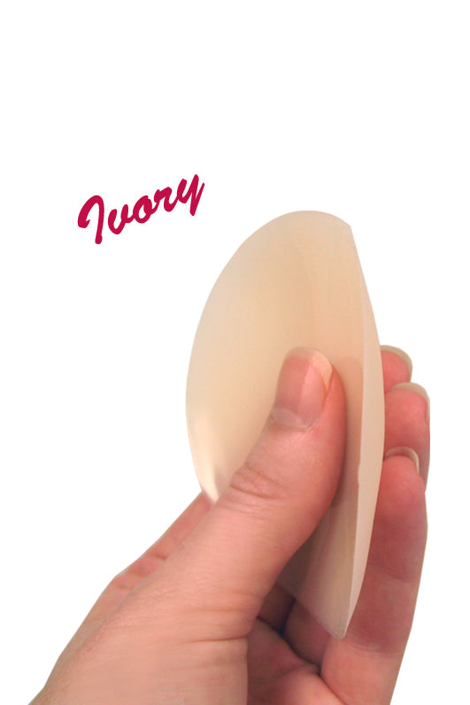 Hand holding a non-adhesive silicone nipple cover in ivory color, showcasing their thin design.