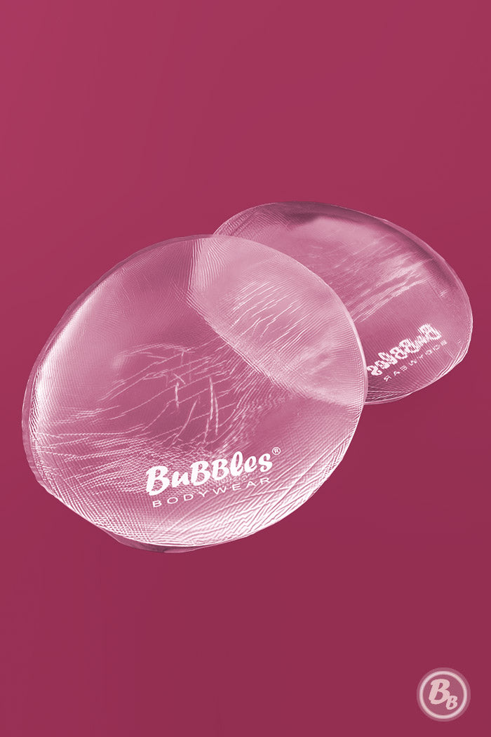 Realistic-feeling, clear, silicone butt pads pictured on a dark pink background.